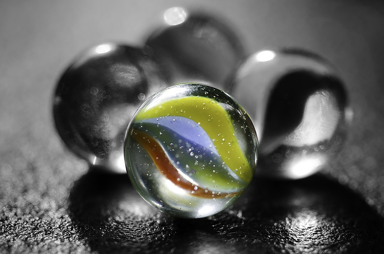 colored marble in front of clear marbles